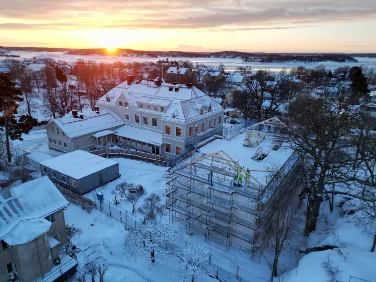 Flygfoto över Vaxö skola med pågående byggnation av annex, vy över Vaxholmsfjärden