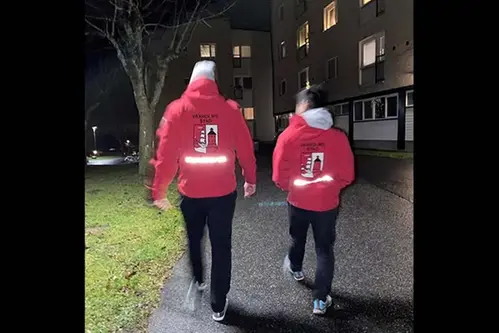 Två nattvandrare med märkta jackor vandrar i Vaxholm på kvällen