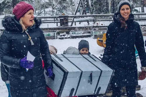 Malin Forsbrand och Maria Carlsson bär en träkista mellan sig i snöfall.